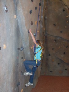 Young girl in blue shirt climbs rockwall